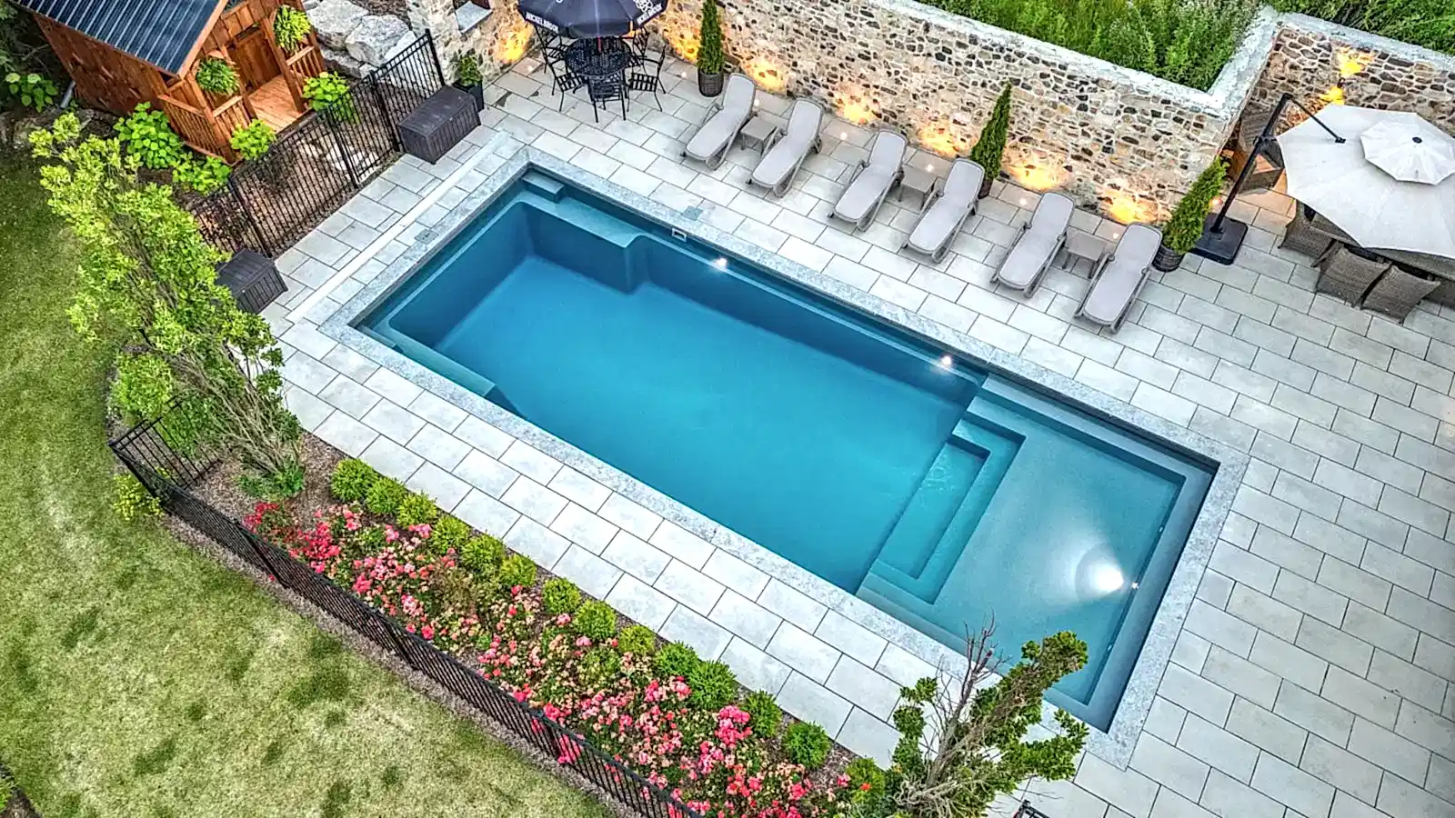 a pool with chairs and a stone wall.